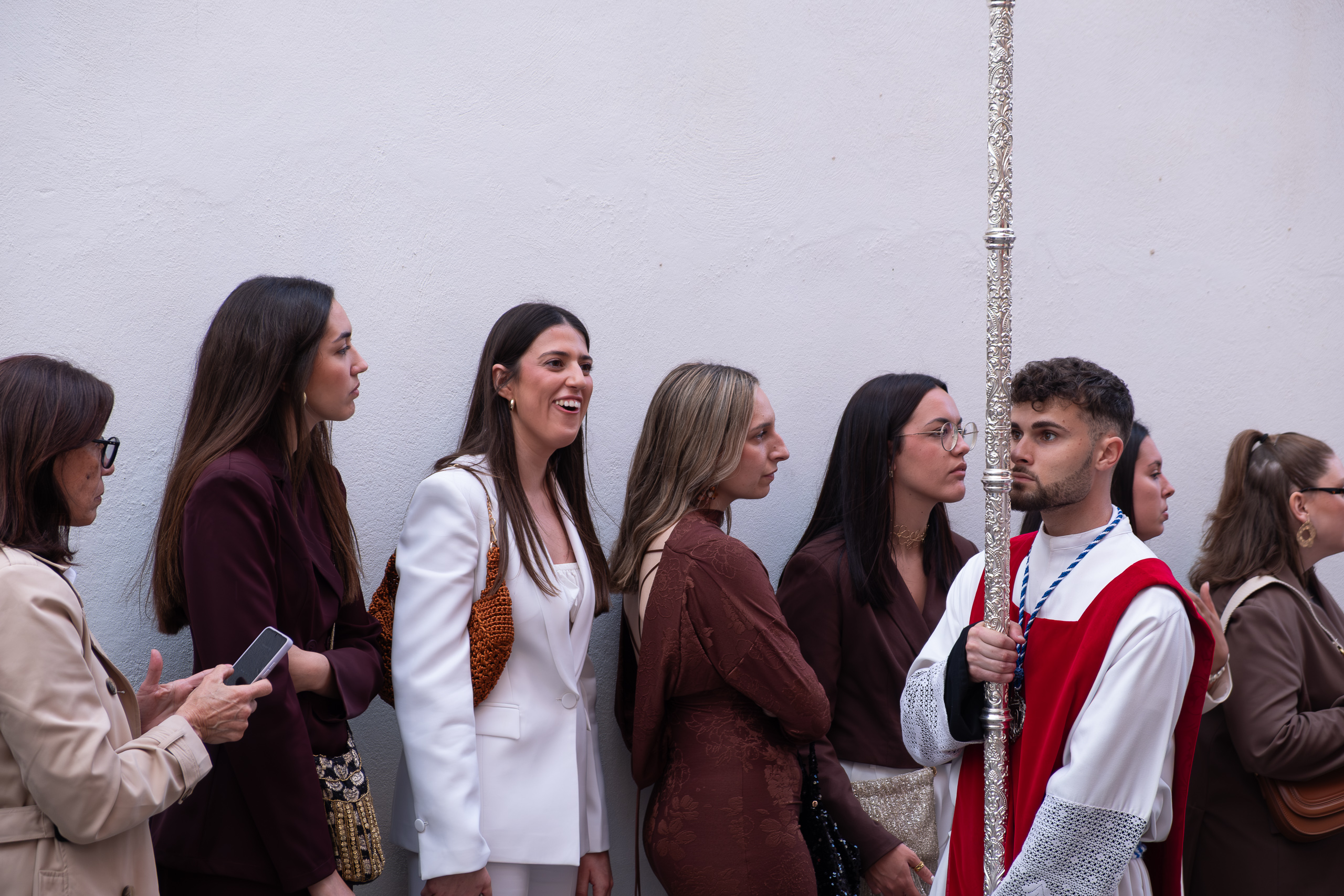 Herausgeputzte Frauen neben einem Nazareno mit Silberstab